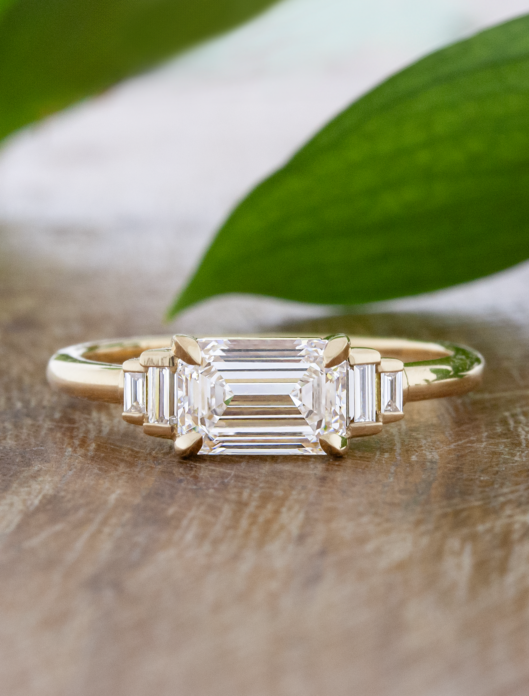 caption:Custom east-west orientation with 1.28ct emerald cut