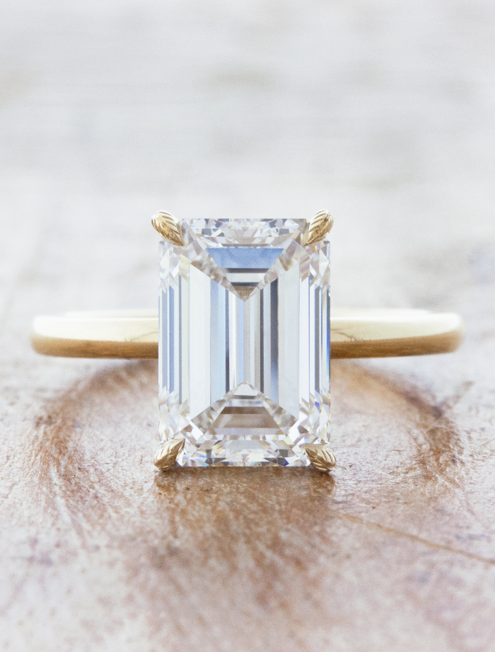 caption:Shown with 4ct emerald cut in 14k yellow gold, customized with leaf engraved prongs