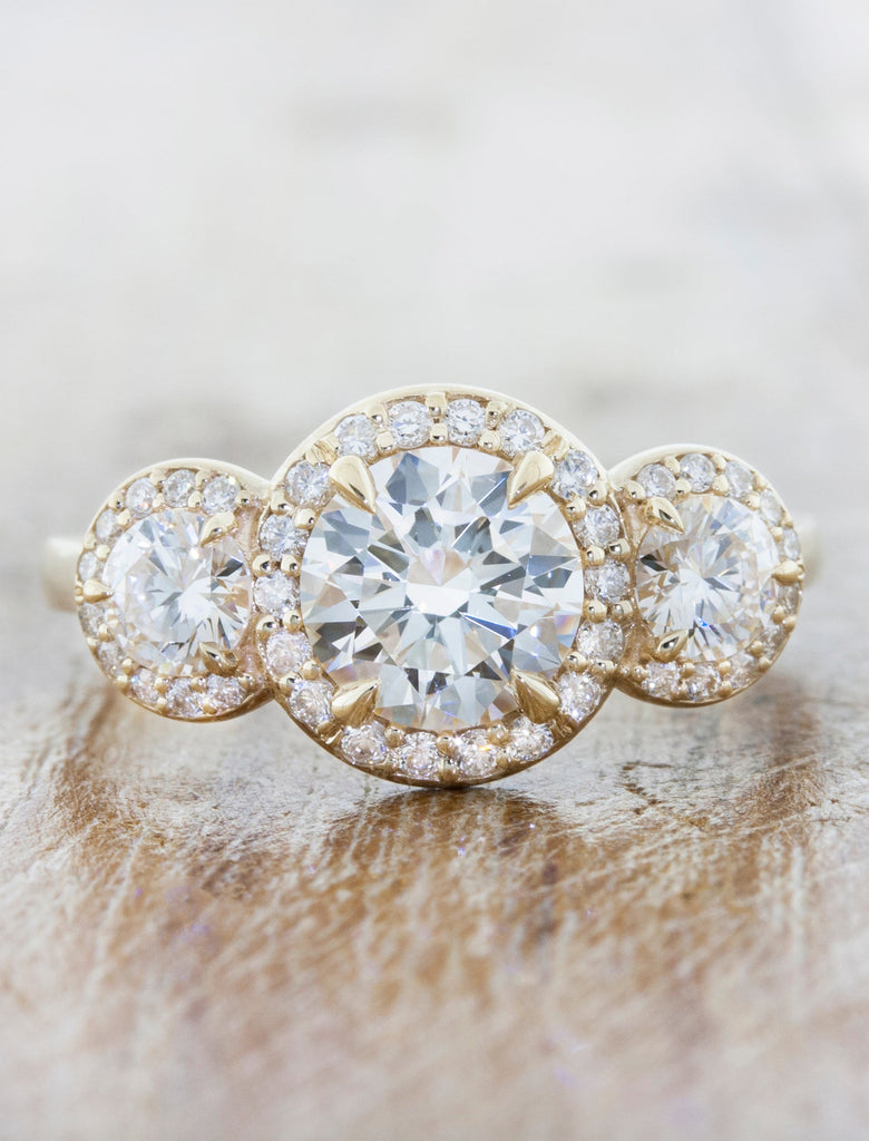 Three stone diamond halo engagement ring. caption:Shown with an 1.2ct round center stone.
