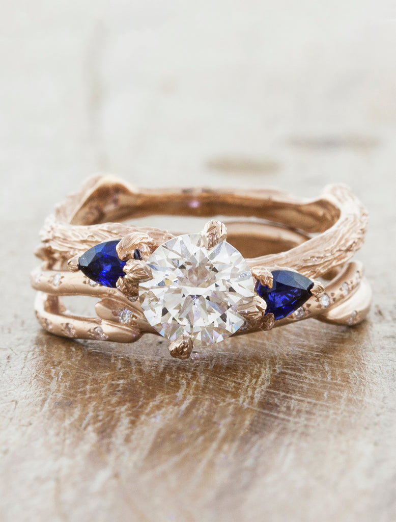 Nature inspired three stone setting. caption:1.00ct. Round Diamond and Sapphire 14k Rose Gold, customized with bark texture. Shown with Selene wedding band