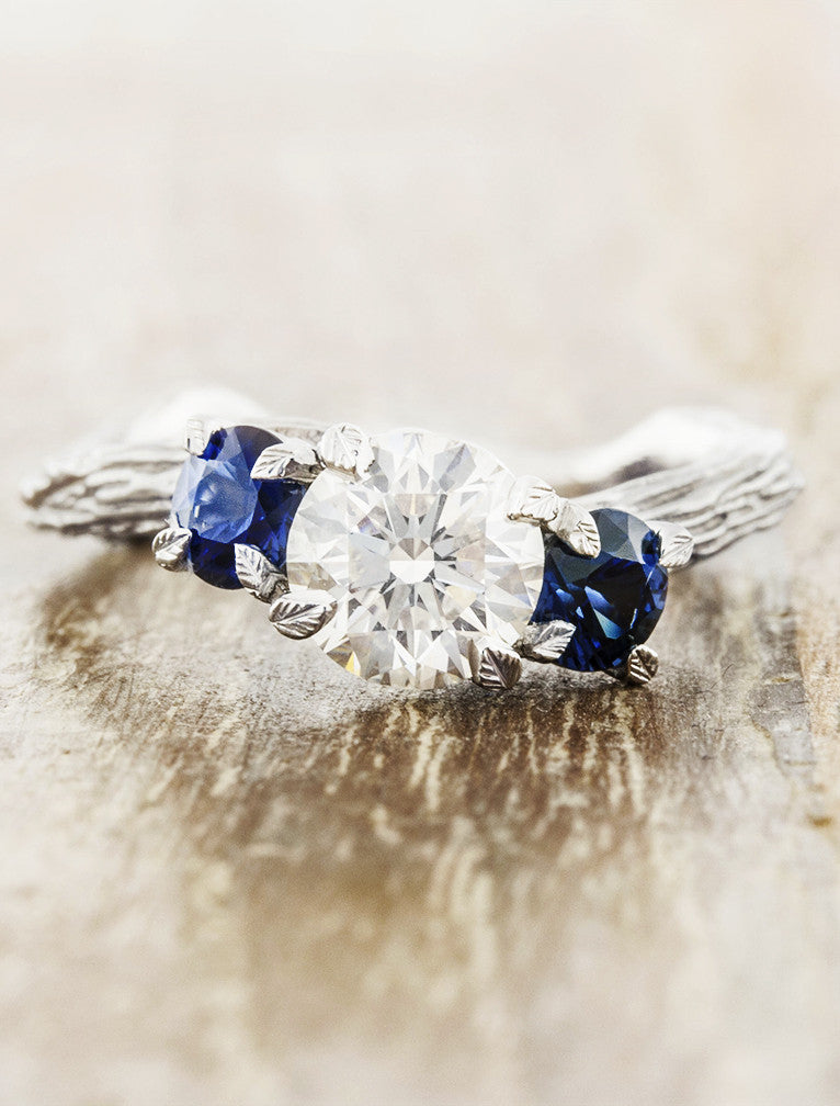 caption:Shown with round diamond & blue sapphire side stones in platinum