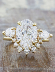 Oval diamond three stone engagement ring, pear side diamonds. caption:3.00ct. Oval Diamond 14k Yellow Gold paired with a custom Antoinette wedding band