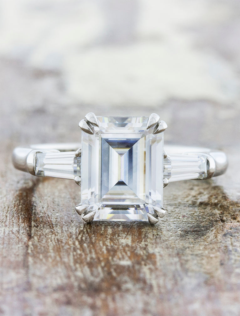 Three stone emerald diamond engagement ring. caption:Shown with a 3ct emerald cut diamond